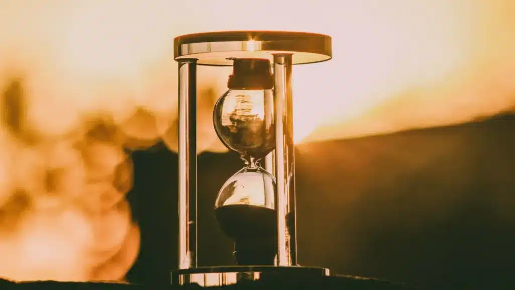 Reloj de arena vintage con luz cálida natural, representando la longevidad saludable y el enfoque pausado de la medicina slow