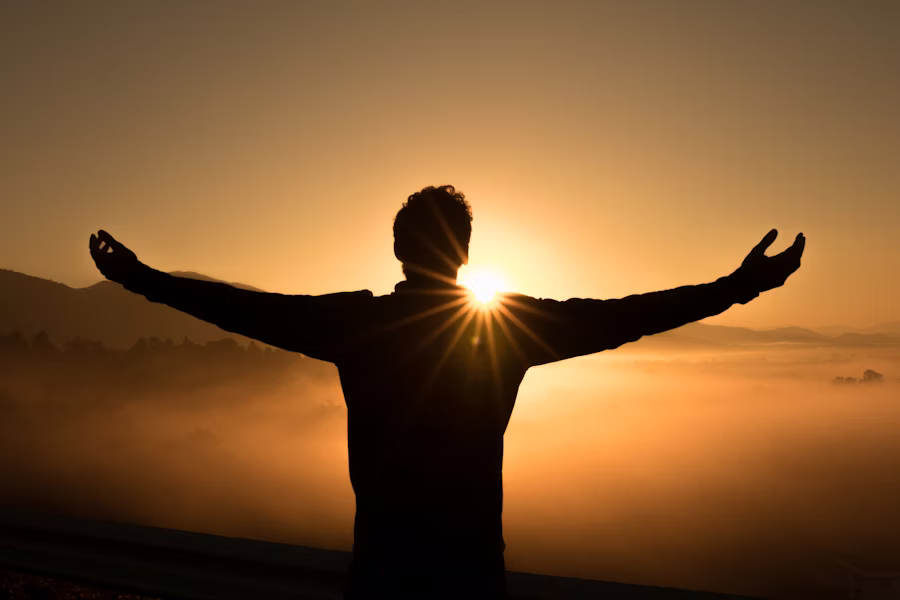 Person embracing the light with open arms, symbolizing the transformative power of humanistic psychology