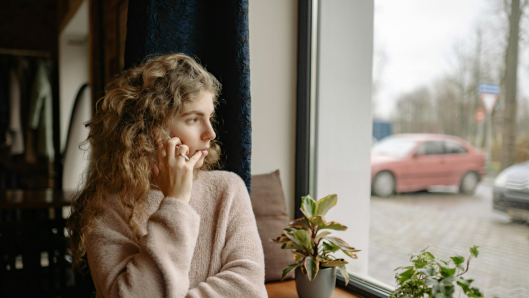 Mujer mirando por la ventana, domingo, triste y pensativa.