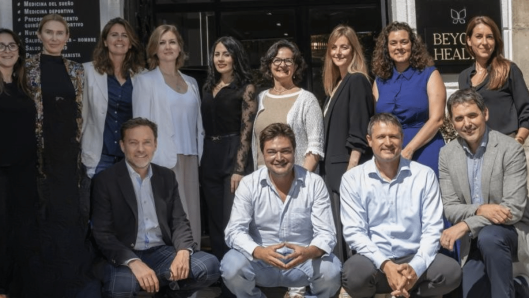 Foto de grupo del equipo de Monarka Clinic (médicos y personal) posando en la entrada de la clínica, con varias personas de pie y otras sentadas, en un entorno exterior con la fachada y el rótulo al fondo.
