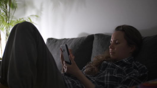 mujer comprando con el teléfono de noche en el sofá a oscuras