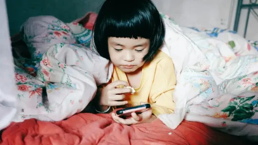 Niña mirando el móvil en la cama